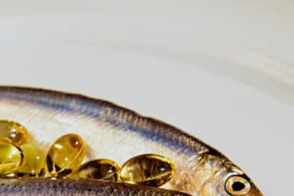 Sprat fish and cod liver oil capsule on a plate.